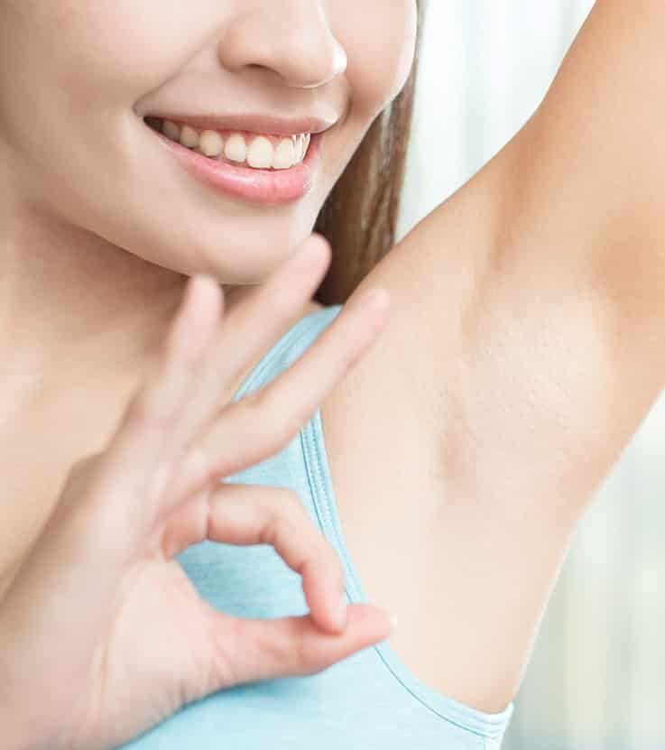 A lady smiling with her one arm up exposing her underarms